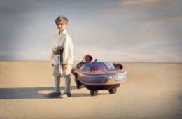 Little Boy Posing At The Side Of Star Wars Luke Skywalker Landspeeder
