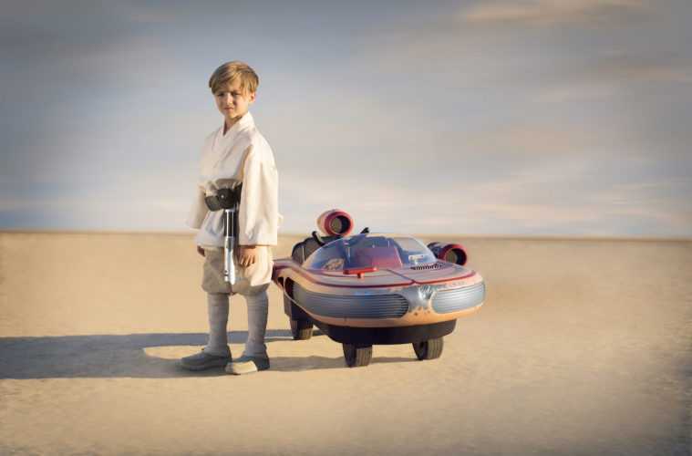 Little Boy Posing At The Side Of Star Wars Luke Skywalker Landspeeder