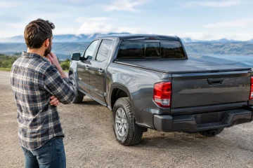 Man Sizing Up A Gray Pickup Truck With A Black Hard Tonneau Cover On The Bed